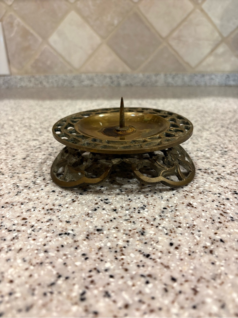 Vintage cast-brass candle holder featuring an ornate filigree openwork base